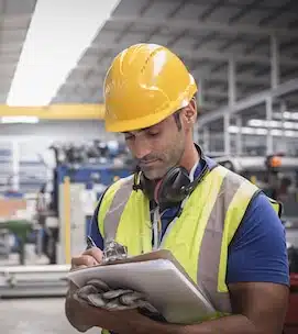 Male worker writing on clipboard in factory